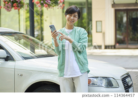 在車前使用智慧型手機的年輕女子 114364457