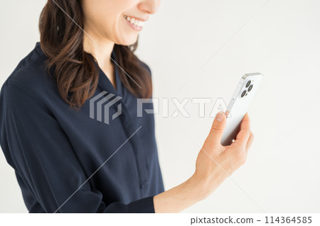 A middle-aged woman who operates a smartphone. (parts) 114364585