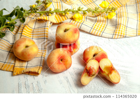 Halves and several whole saturn peaches or flat peach on white wooden background.. Halves and several whole saturn peaches or flat peach on white wooden background.. 114365020