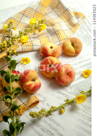 Several whole saturn peaches or flat peach on white wooden background.. 114365023