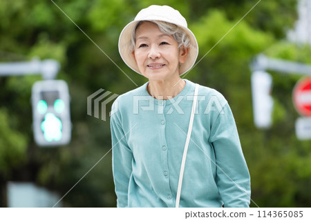 A gray-haired senior woman walking with a cane 114365085