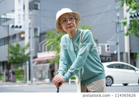 An elderly woman leaning on a cane and thinking An elderly woman leaning on a cane and thinking 114365626