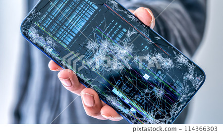 一個從摩托車上掉下來的男人，展示了一部壞掉的智能手機 114366303