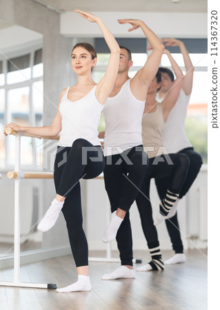 Woman working on Passe Developpe at barre at group ballet class 114367320