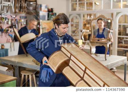 Male furniture maker sanding vintage commode in workshop 114367390