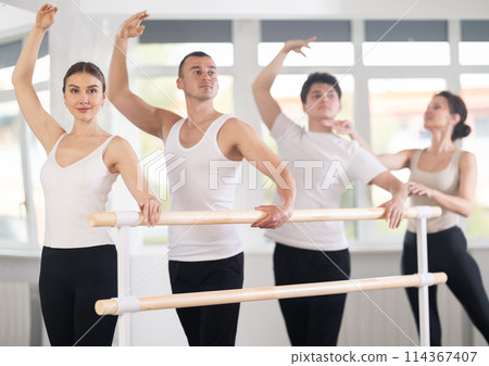 Female trainer corrects dancers at barre 114367407