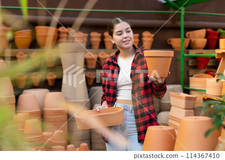 Young woman chooses flower pots for indoor plants Young woman chooses flower pots for indoor plants 114367410