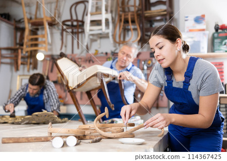 Restorer woman carefully cleans dirt and dust from carved wooden decor element Restorer woman carefully cleans dirt and dust from carved wooden decor element 114367425