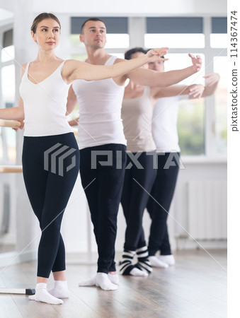Woman maintaining fifth position during group ballet workout 114367474