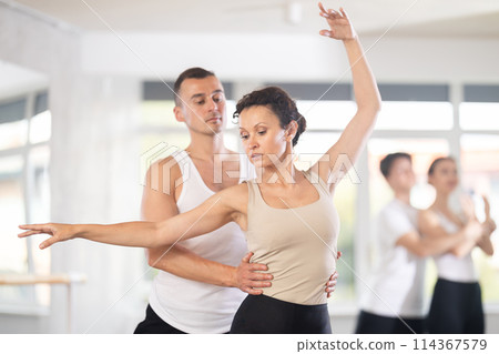 Portrait of young man practicing in classical ballet with young beautiful woman in black and white clothing in ballet hall 114367579