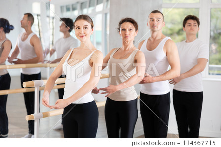 Group of dancers stand in first position at barre 114367715