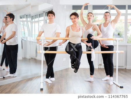 Group of adult students of ballet class posing at barre in studio 114367765