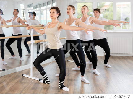 Woman practicing demi plie at barre at group ballet class 114367767