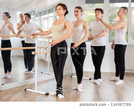 Ballet students practicing basic positions at barre with instructor 114367789