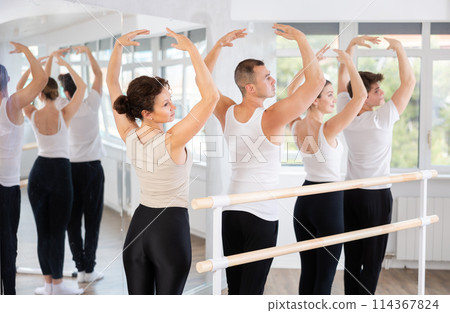 Group of dancers stand in first position at barre 114367824