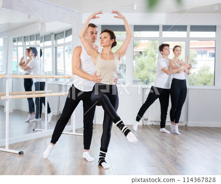 Ballet dancer providing support of female partner in challenging movements Ballet dancer providing support of female partner in challenging movements 114367828