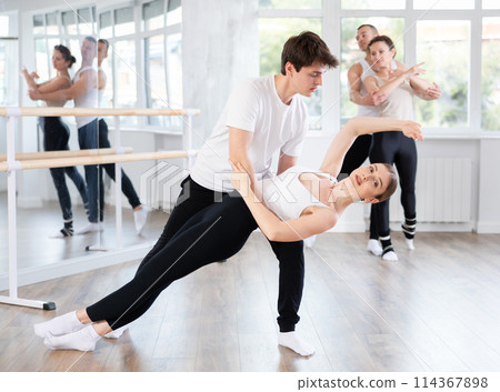 Young ballet dancer supporting female partner in challenging movements 114367898