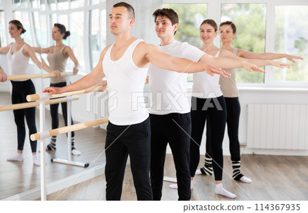 Group of dancers stand in second position at barre 114367935