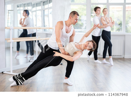 Ballet partners mastering paired technique at group class in studio Ballet partners mastering paired technique at group class in studio 114367948