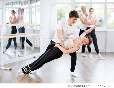 Young ballet dancer supporting female partner in challenging movements Young ballet dancer supporting female partner in challenging movements 114367979