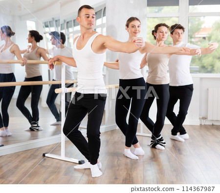 Man performing demi plie at barre at group ballet class 114367987