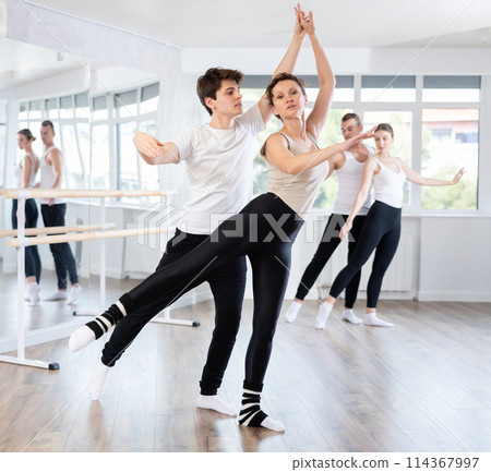 Young ballet dancer supporting female partner in challenging movements 114367997