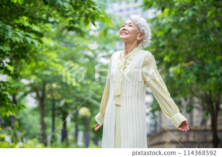 Senior woman looking up at the sky and taking a deep breath Senior woman looking up at the sky and taking a deep breath 114368592