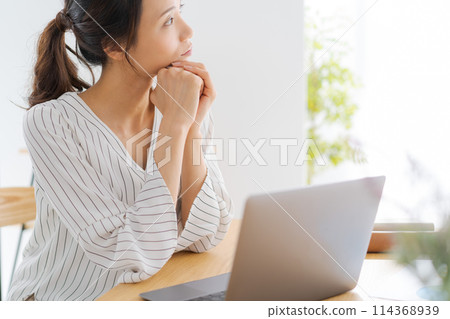 A woman looking to the side with her chin in her hand A woman looking to the side with her chin in her hand 114368939