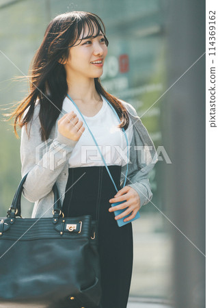 A woman in her 20s with a cute smile walking through the city A woman in her 20s with a cute smile walking through the city 114369162