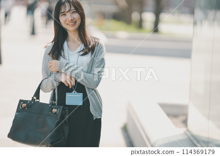A working woman in her 20s with a cute smile walking through the city 114369179