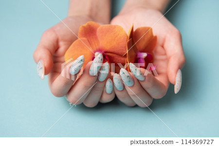 Female hands with blue nail design on blue pastel background 114369727