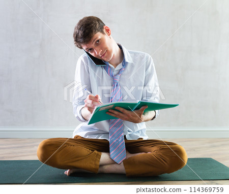 Young guy making notes while talking on phone Young guy making notes while talking on phone 114369759