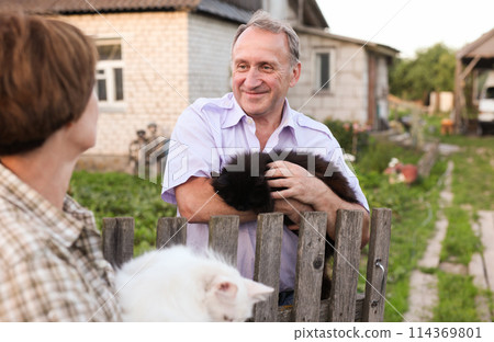 Farm neighbors with cats in their arms talking 114369801