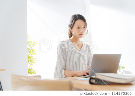 A woman in her 30s working remotely 114370365