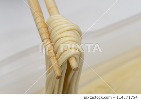 Water-soaked pasta, lifted with chopsticks 114371754