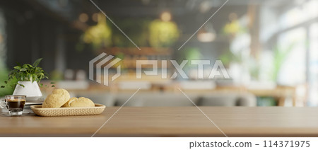A wooden tabletop features a bread basket and a coffee cup in a modern restaurant or coffee shop. 114371975