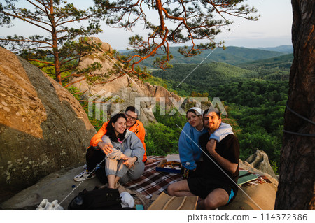 happy friends eating pizza at the cliff with beautiful mountain view 114372386