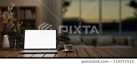 A white screen laptop computer mockup on a wooden table in a modern dark living room. A white screen laptop computer mockup on a wooden table in a modern dark living room. 114372518