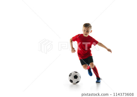 Athletic, sportive boy in uniform training dribbling technique in motion against white studio background. Dynamic shot. Athletic, sportive boy in uniform training dribbling technique in motion against white studio background. Dynamic shot. 114373608