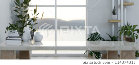A coffee table surrounded by indoor houseplants in a minimal contemporary room. 114374315