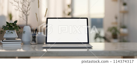 A laptop computer mockup and accessories on a coffee table in a contemporary living room. 114374317