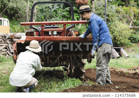 Men and women taking care of a tractor Men and women taking care of a tractor 114375686