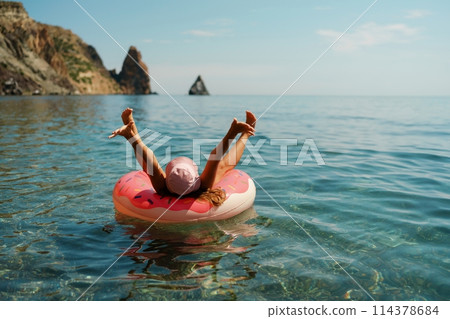Summer vacation woman in hat floats on an inflatable donut mattress. Happy woman relaxing and enjoying family summer travel holidays travel on the sea. 114378684