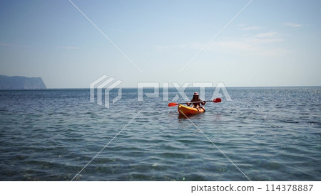 Kayak sea woman. Young attractive brunette woman with long hair in red swimsuit, swimming on kayak. Summer holiday vacation and travel concept. 114378887