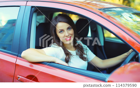 Happy smiling female driver sitting behind the wheel of car Happy smiling female driver sitting behind the wheel of car 114379590
