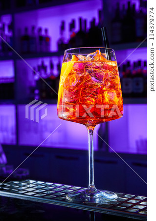 Alcoholic cocktail with ice and a piece of orange on the bar counter Alcoholic cocktail with ice and a piece of orange on the bar counter 114379774