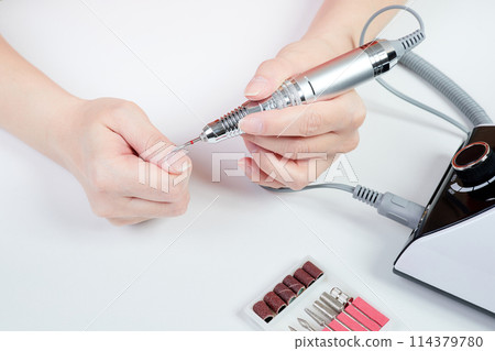 A girl gives herself a manicure using a nail drill A girl gives herself a manicure using a nail drill 114379780