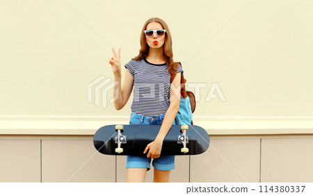 Portrait of cheerful young woman with skateboard in the city Portrait of cheerful young woman with skateboard in the city 114380337