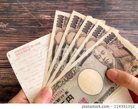 A woman holding a bankbook and 50,000 yen A woman holding a bankbook and 50,000 yen 114381352