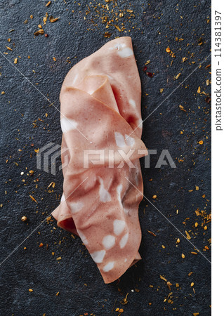 high angle view of a slice of mortadella high angle view of a slice of mortadella 114381397
